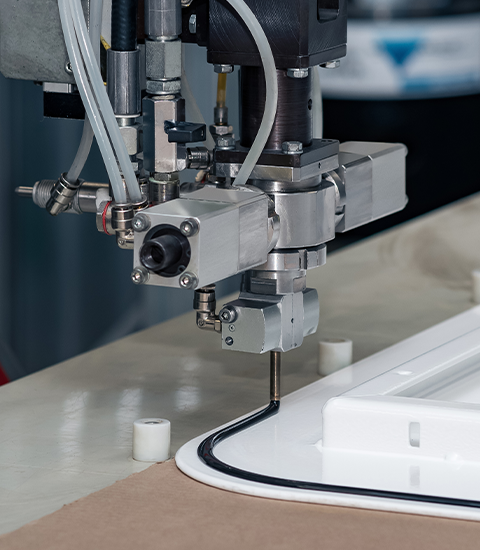 Precision-engineered applicator gun dispensing adhesive on a production line.